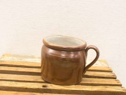 Handcrafted brown ceramic mug on rustic wooden surface, highlighting artisanal craftsmanship and natural beauty.