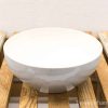 Elegant white bowl on rustic wooden table, perfect for serving and displaying food.