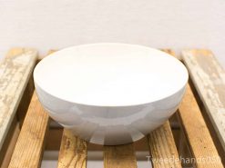 Elegant white bowl on rustic wooden table, perfect for serving and displaying food.