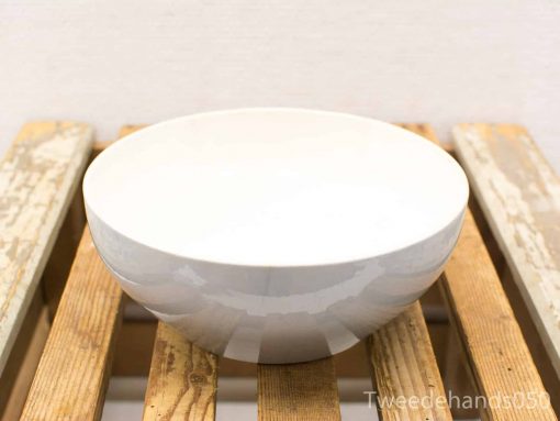 Elegant white bowl on rustic wooden table, perfect for serving and displaying food.