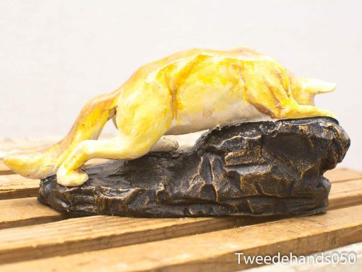 Elegant resting canine sculpture on a rocky base, showcasing charm and grace.