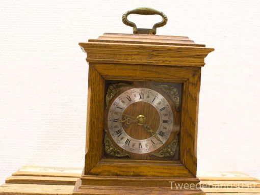 Elegant vintage wooden table clock with intricate details and Roman numeral dial.