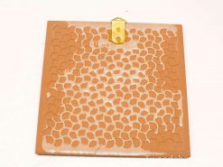 Elegant terracotta wall decor with honeycomb pattern and metallic hook for stylish display.