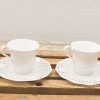 Elegant white teacups with saucers on rustic wood, perfect for tea moments.