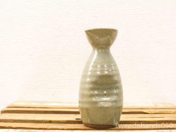 Handmade ceramic vase with elegant organic shape and subtle ribbed texture in earthy tones.