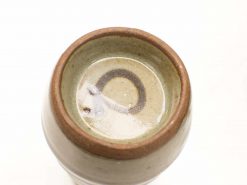 Handcrafted ceramic vessel with unique glaze details and earthy tones, perfect for decor or practical use.