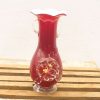 Elegant red vase with floral design and rustic wooden base, perfect for stylish decor.