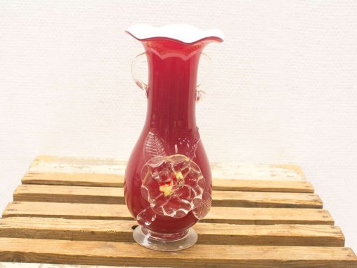 Elegant red vase with floral design and rustic wooden base, perfect for stylish decor.