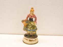 Charming vintage ceramic figurine of a woman with a basket in traditional attire.