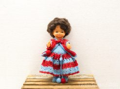 Charming vintage doll in colorful crocheted dress, evoking nostalgia and childhood joy.