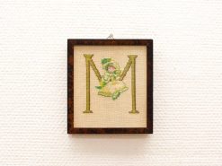 Vintage embroidery featuring a whimsical girl in pastel dress and letter M, perfect decor.