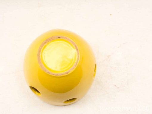 Bright yellow ceramic planter with holes, ideal for decor or candle holder use.