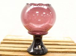 Elegant pink glass vase on a black pedestal, perfect as a decorative centerpiece.