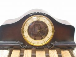 Elegant vintage wooden mantel clock with intricate carvings and a classic golden dial.