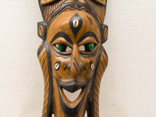 Vibrant wooden mask with green eyes, intricate craftsmanship, and a joyful smile for cultural significance.