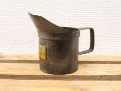 Nostalgic vintage metal measuring jug with yellow label, perfect for precise pouring in rustic kitchens.