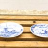 Decorative blue and white porcelain plates featuring Dutch windmill landscapes on a rustic wooden surface.