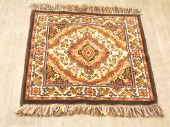 Vintage diamond pattern rug with floral designs in warm tones, perfect for home decor.