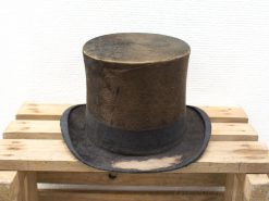 Vintage brown top hat on rustic wooden palette, showcasing timeless elegance and historical charm.