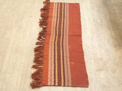 Handwoven vintage rug in red and brown, featuring intricate patterns and warm tones.