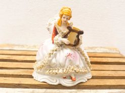 Elegant porcelain lady with harp, vintage decor piece showcasing artistry and charm.