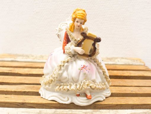 Elegant porcelain lady with harp, vintage decor piece showcasing artistry and charm.