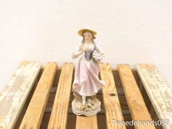 Charming vintage figurine of a woman in pink dress holding a flower basket.