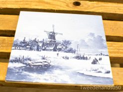 Serene winter landscape with a traditional windmill, ice skaters, and quaint snow-covered houses.