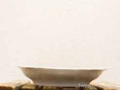 Elegant white ceramic plate on rustic wooden surface, perfect for serving bread or fruit.