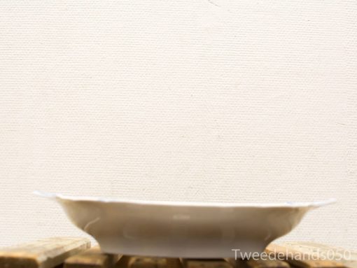 Elegant white ceramic plate on rustic wooden surface, perfect for serving bread or fruit.