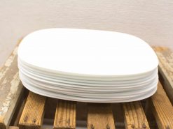 Elegant white oval plates stacked on rustic wooden surface for a stylish dining experience.