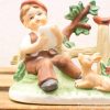 Vintage porcelain figurine of a joyful boy with his playful dog in nature.