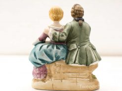 Charming ceramic figurine of a loving couple, showcasing intimacy and vintage elegance.