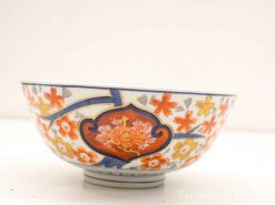 Elegant ceramic bowl with vibrant floral designs in orange, yellow, and blue glaze.