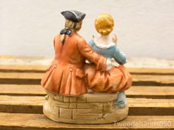 Charming vintage ceramic couple figurine capturing an intimate moment of conversation and connection.