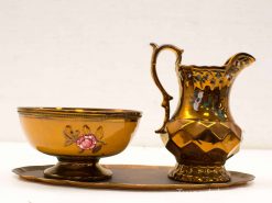 Elegant vintage set: bowl, pitcher, and tray in warm golden hues with floral details.