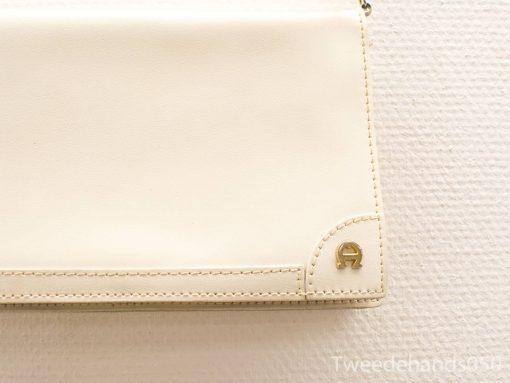 Elegant cream leather handbag with gold emblem, perfect for any occasion.