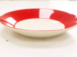 Vintage ceramic plate with glossy red rim and cream interior, perfect for stylish serving.