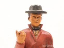 Handcrafted figurine of a man in a vibrant red coat and black hat.