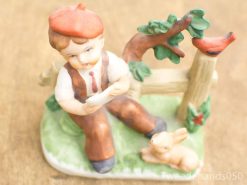 Curious boy figurine exploring nature with rabbit, tree, and vibrant countryside elements.