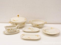 Elegant porcelain dining set with floral design, features serving dish, bowls, gravy boat, and platters.