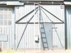 Weathered wooden building with ladder, double doors, and vintage charm in natural surroundings.