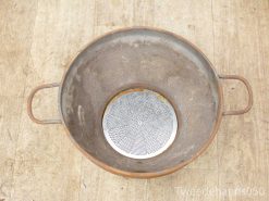 Vintage metal basin with perforated strainer, showcasing rustic charm and functionality for kitchens.