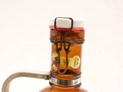 Vintage amber glass bottle with metal cap and decorative labels, ideal for collectors.