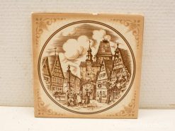 Charming ceramic plate featuring a vintage village scene with traditional houses and a clock tower.