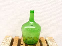 Elegant vintage green glass bottle on rustic wooden surface, showcasing charm and history.