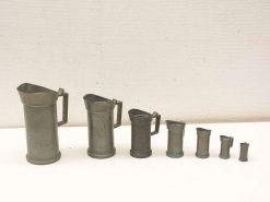 Vintage metal measuring jugs in various sizes, perfect for nostalgic kitchens and practical use.