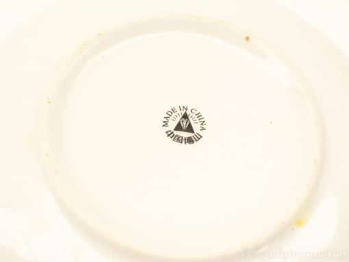 Glossy white ceramic dish with Made in China logo and subtle wear marks.