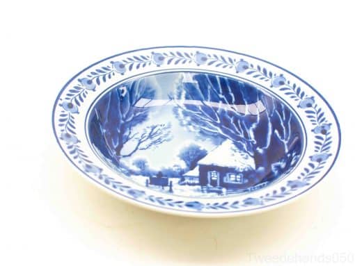 Charming blue decorative plate depicting a winter cottage scene with intricate detailing.