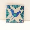 Vibrant rooster tile with folkloric design, showcasing detailed patterns in blue and green hues.